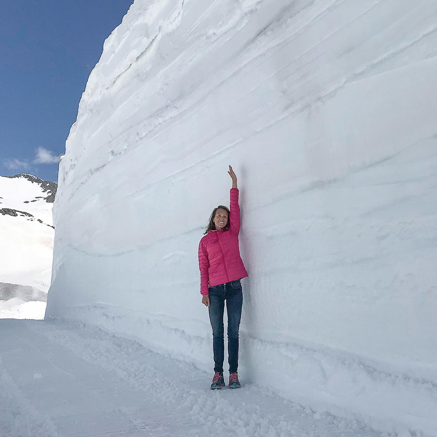 Une femme lève le bras pour montrer la hauteur de neige qui la dépasse du double de sa taille à La Rosière