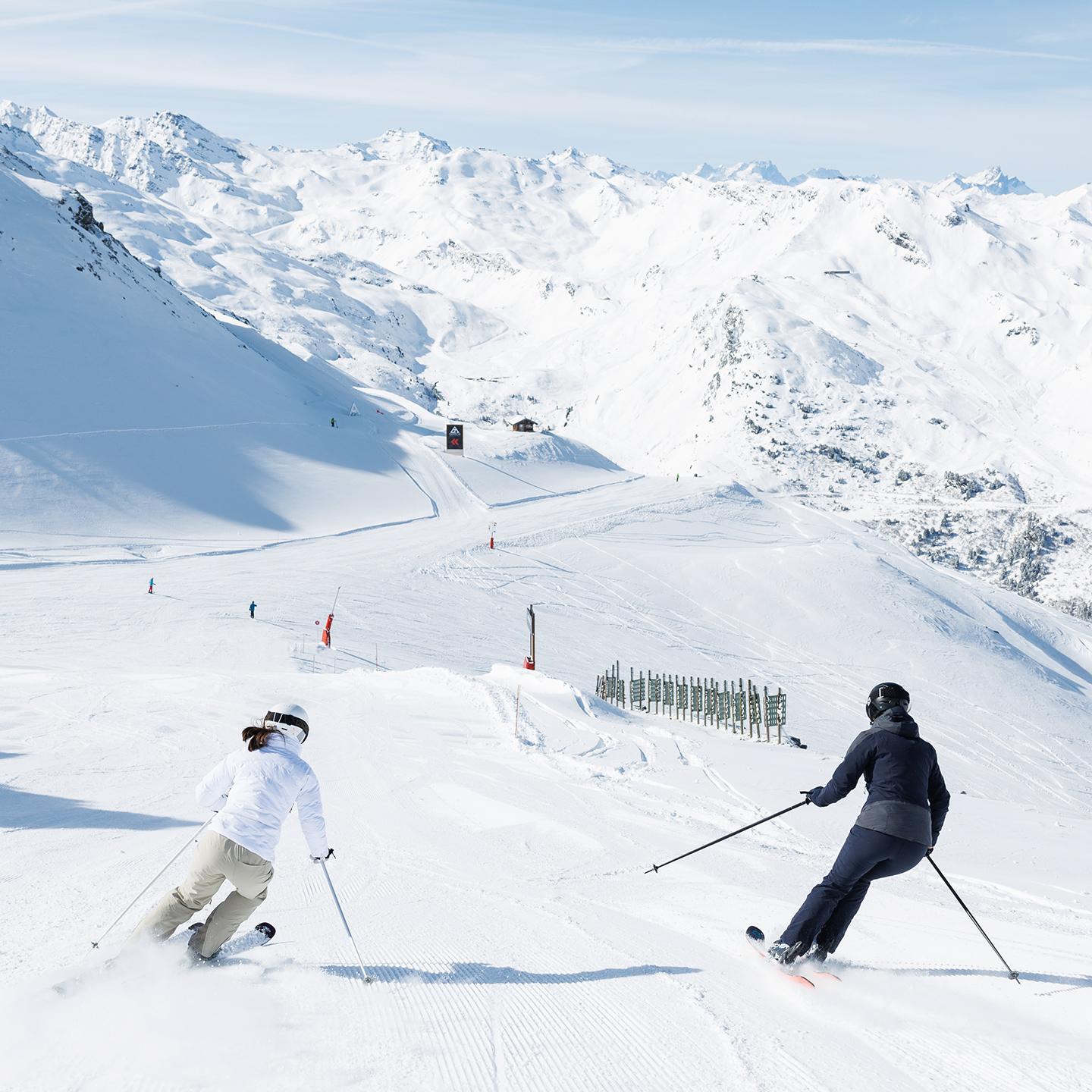 Deux personnes dévalent les pistes de Méribel en ski alpin