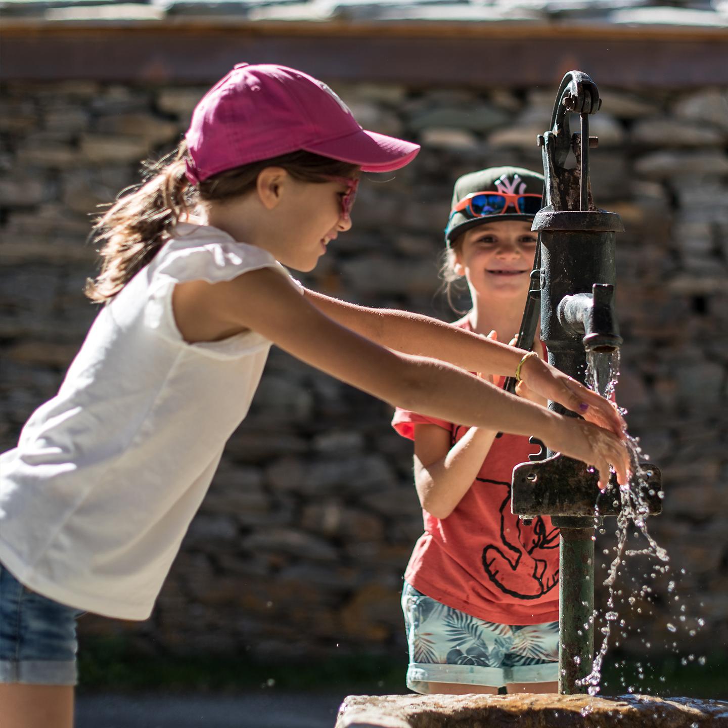 Deux fillettes puisent de l'eau depuis une fontaine publique en Haute Maurienne