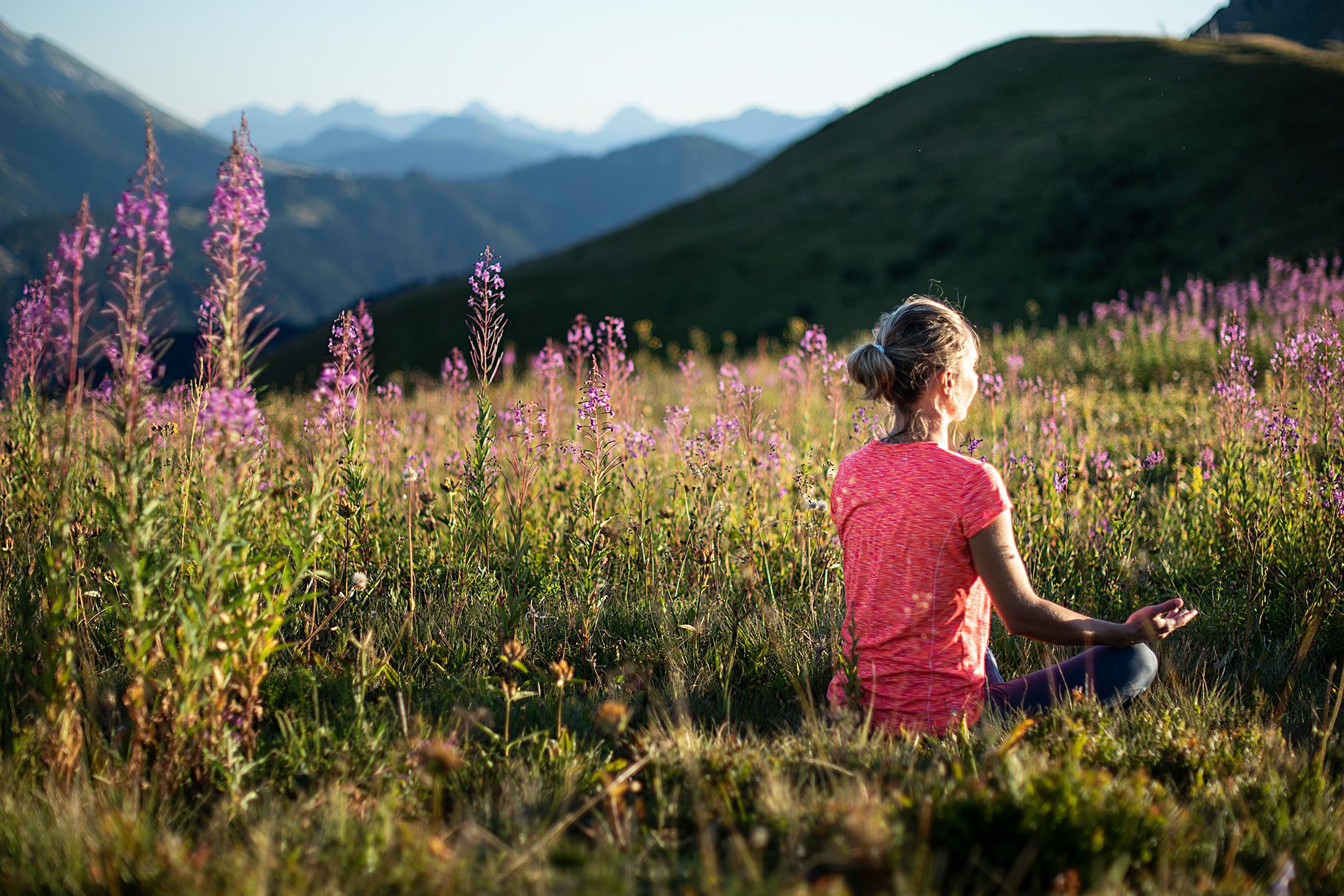 Femme faisant du yoga dans un champ au coeur des Aravis 