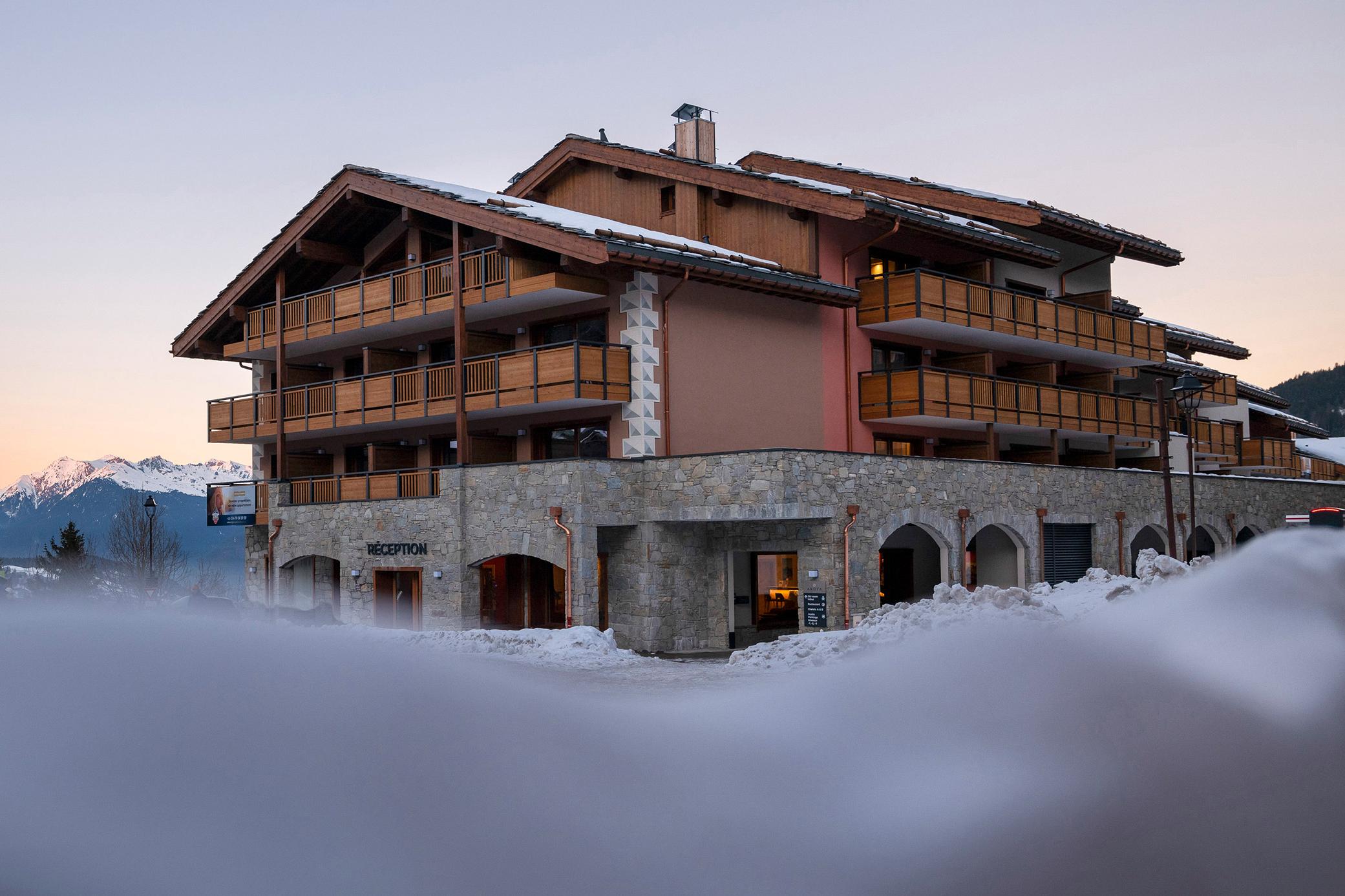 Vue sur la résidence Akoya à Valmorel en fin de journée, par un paysage enneigé