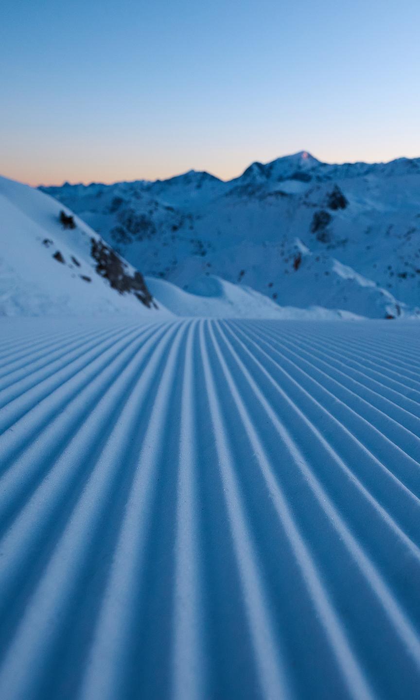 Traces dans la neige suite au passage d'une dameuse sur piste de Paradiski 