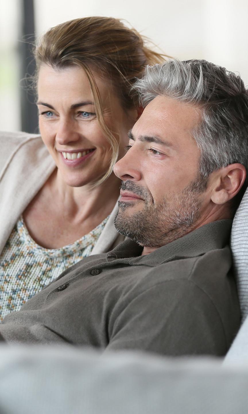 Un couple est en train de regarder quelque chose sur une tablette, assis sur leur canapé - Projet Investir à la montagne