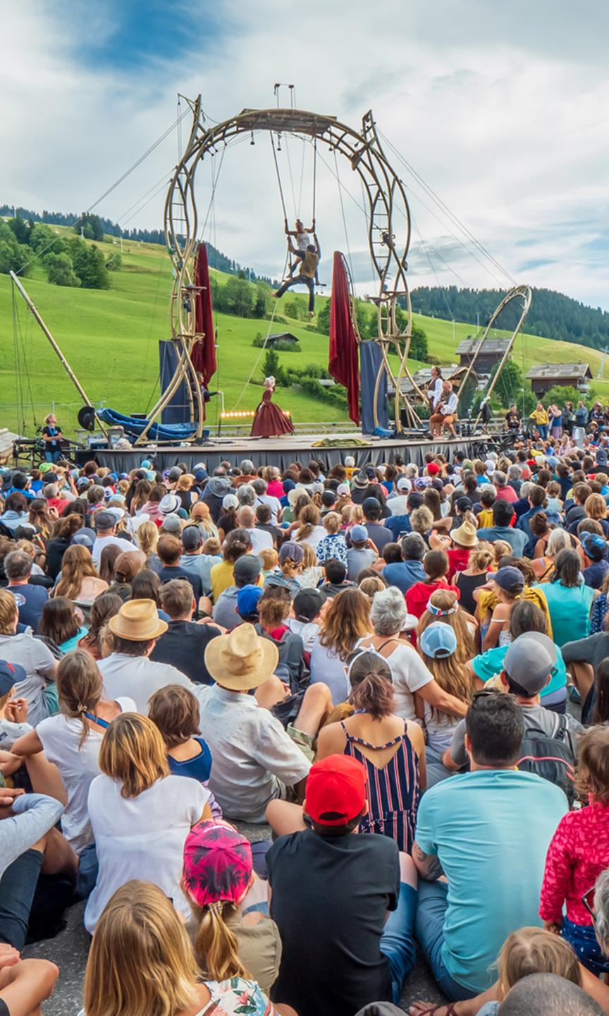 Une foule de spectateurs regarde 2 artistes effectués un spectacle de cirque  lors de l'évènement annuel aux Bonheur des Mômes au Grand-Bornand