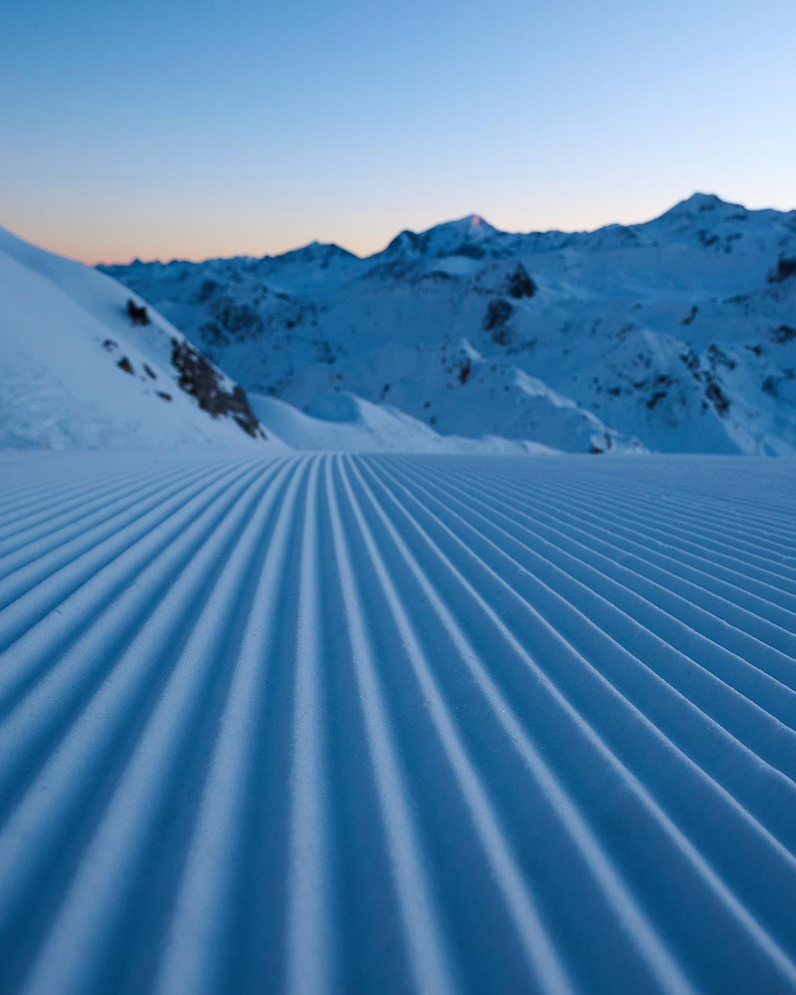 Traces dans la neige suite au passage d'une dameuse sur piste de Paradiski 