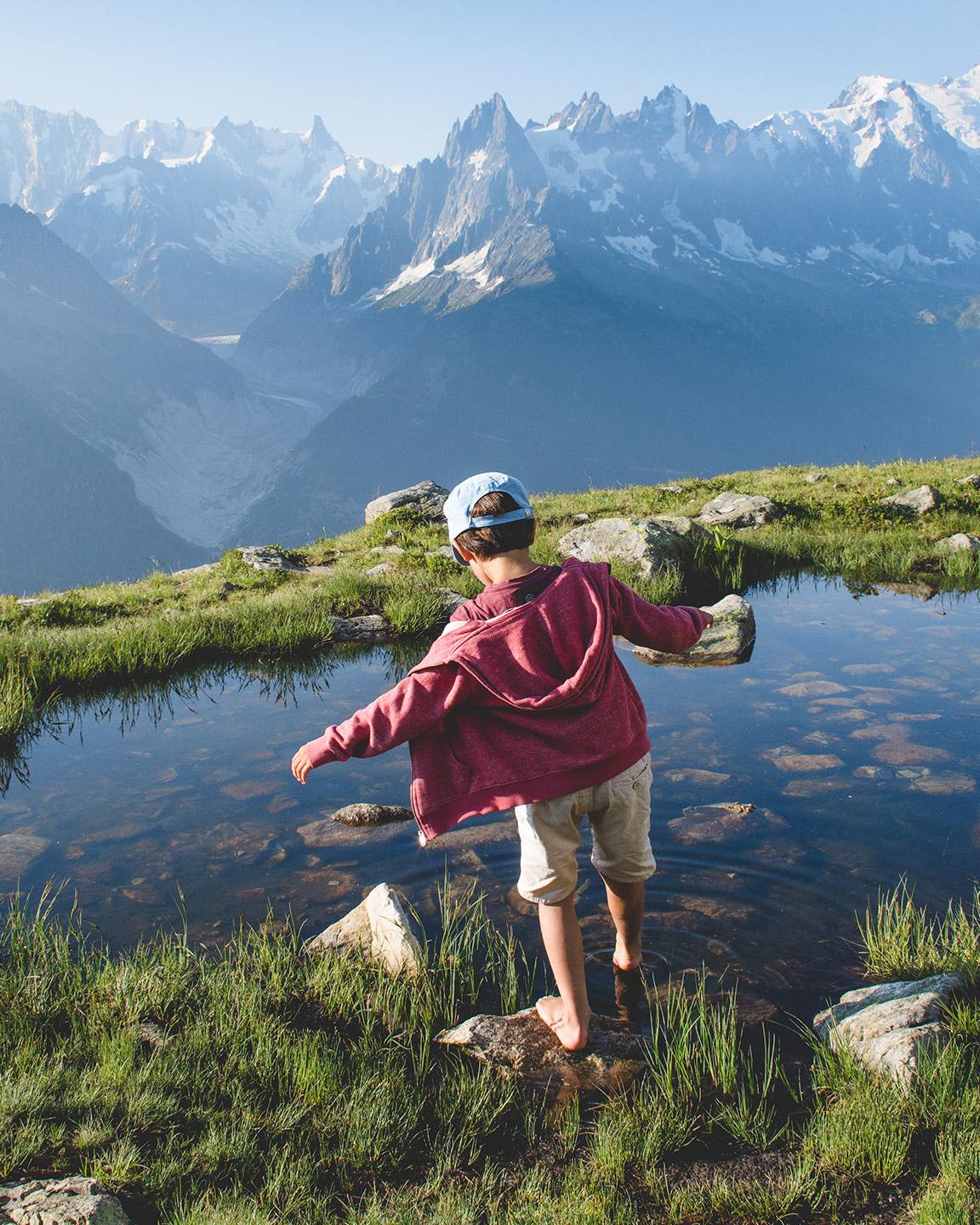 Petit garçon entrain de tremper ses pieds dans un lac de montagne