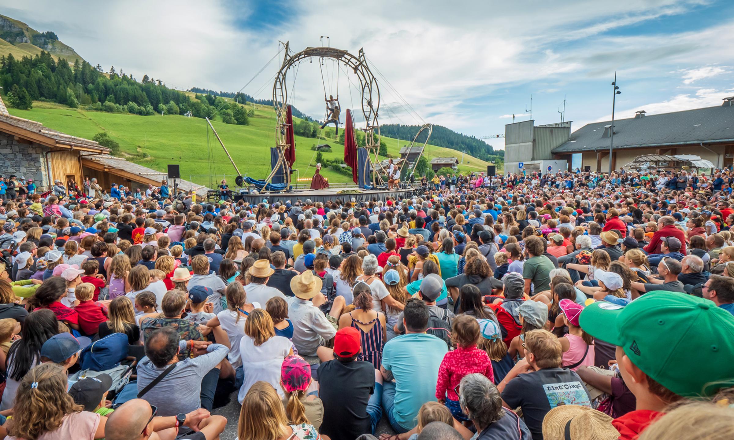 Une foule de spectateurs regarde 2 artistes effectués un spectacle de cirque  lors de l'évènement annuel aux Bonheur des Mômes au Grand-Bornand