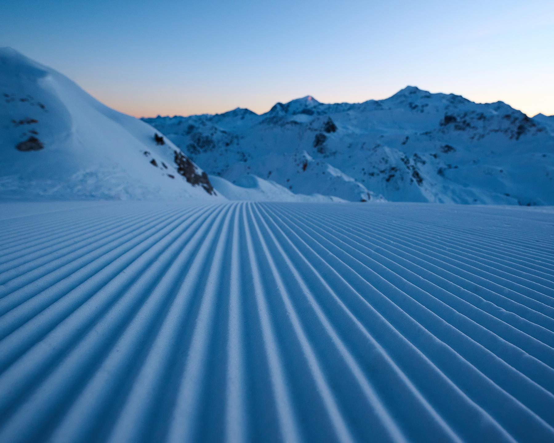 Traces dans la neige suite au passage d'une dameuse sur piste de Paradiski 